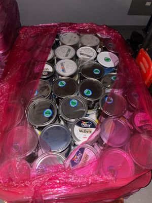 many cans of paint in a plastic bag on the floor