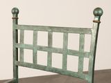 a green metal bed frame with a wooden headboard