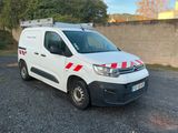La camionnette blanche est garée sur le parking, près d'un mur.