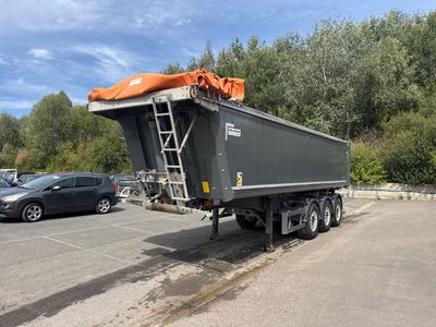 un camion-benne garé sur un parking, avec une voiture en arrière-plan