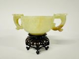 un vase jaune posé sur un socle noir, sur un fond blanc
