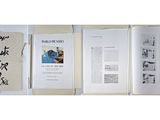 three books are open on a table with papers and a bag