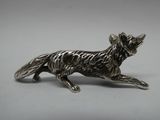 une image représentant une figurine de chien en argent sur fond blanc