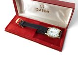 une photo d'une montre Omega dans un coffret rouge, avec un bracelet noir