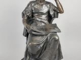 a statue of a woman sitting on a chair with her hand on her head