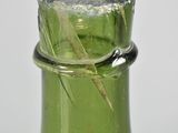 a green glass bottle with a small crack in the top