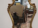 a mirror hanging on the wall with a man sitting on a bench in front of it