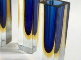 three blue and yellow vases sitting on a white surface