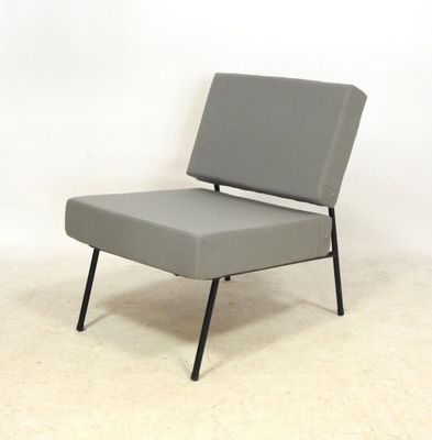chaise grise aux pieds noirs, posée sur un sol blanc