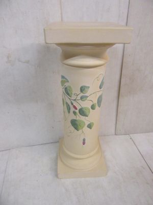 a white vase with green leaves on it sitting on a table