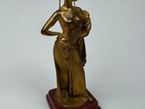 bronze statue of a woman holding a basket of flowers on a wooden base