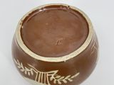 a brown and white bowl on a white surface