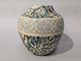 a blue and green vase sitting on a white surface