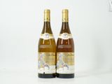 deux bouteilles de vin posées l'une à côté de l'autre sur une surface blanche