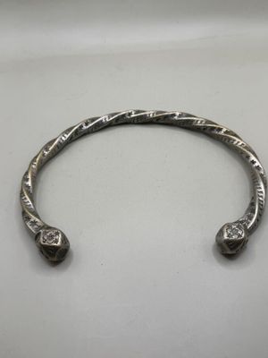a close up of a silver bracelet on a white surface