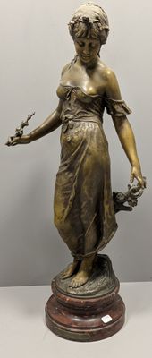 statue en bronze d'une femme tenant un oiseau sur un piédestal