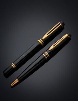 une paire de stylos à plume noirs et dorés sur fond noir