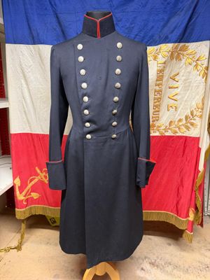 une photo d'un manteau militaire posé sur un mannequin devant un drapeau