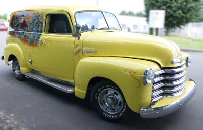 a yellow truck with graffiti painted on it driving down the street