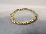 a close up of a gold bracelet on a white surface