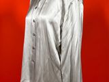 shiny silver shirt on a mannequin stand against a red wall