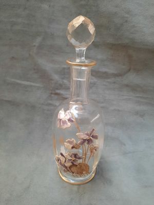 une bouteille en verre transparent contenant des fleurs, posée sur une table