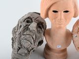 three clay heads of different shapes and sizes on a table