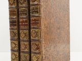 trois vieux livres posés l'un sur l'autre sur une surface blanche