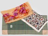 two scarves with floral designs on them sitting on a table