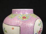 a pink vase with a floral design on it on a black background
