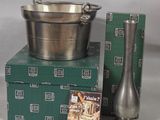 a silver bowl and a silver vase on a stack of green boxes