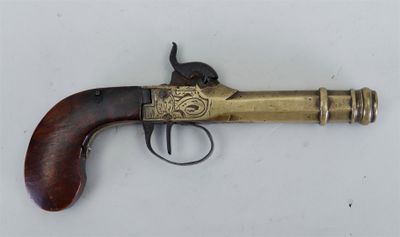 un vieux revolver en laiton avec une crosse en bois, posé sur une surface blanche