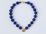 un bracelet en perles bleues orné d'une breloque en forme de pièce d'or