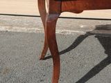 a small table with a wooden top sitting on the pavement