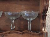 three wine glasses sitting on top of a wooden shelf
