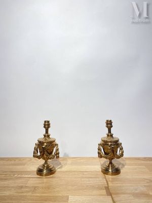 une paire de bougeoirs anciens en laiton posés sur une table en bois devant un mur blanc