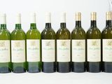 six bouteilles de vin sont alignées sur une surface blanche