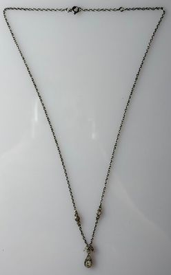 a silver necklace with a cross on a chain on a white surface