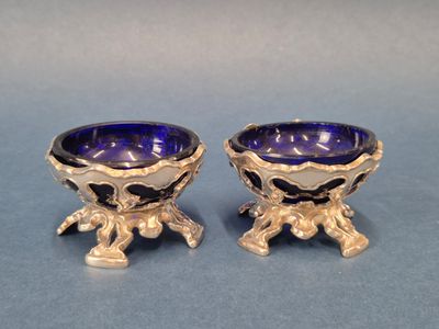 paire de bols en verre argenté et bleu posés sur des socles, sur fond bleu