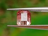 un gros plan sur un diamant rose en train d'être taillé à l'aide d'une paire de pinces