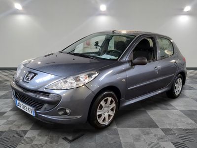 La petite voiture grise est garée dans le garage, sur un sol à damier.