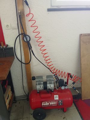 a red air compressor sitting on the floor next to a window