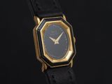 a close up of a black and gold watch on a black background