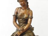 bronze statue of a woman sitting on a rock with a dog