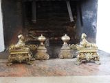 four brass figurines sitting in front of a fire place