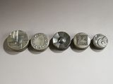 quatre types de pièces différents sont disposés en rangée sur une surface blanche