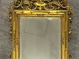 un miroir au cadre doré ouvragé accroché à un mur sur fond blanc