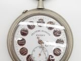 une montre de poche en argent posée sur une surface blanche, sur fond blanc