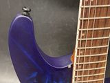 a close up of a guitar with a blue body on a gray background