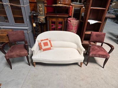 a white couch and chairs in a room with a bookcase